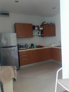 a kitchen with wooden cabinets and a stainless steel refrigerator at Bonanza in Ban Khanong Phra Klang (1)