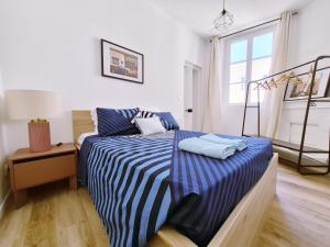 a bedroom with a bed with a blue and white striped sheets at Le 17eme - Centre Historique in Auch