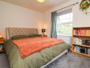 a bedroom with a bed with an orange blanket and a window at Manning's View in Barnstaple