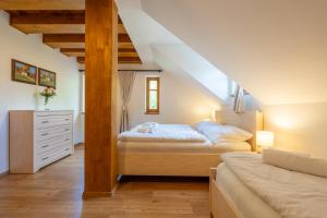 a bedroom with two beds and a dresser in a attic at Apartmány Jezerné in Velké Karlovice