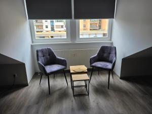 two chairs and a table in a room with windows at Meisterjäger Akademie in Mellrichstadt