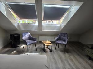 two chairs and a table in a room with two windows at Meisterjäger Akademie in Mellrichstadt