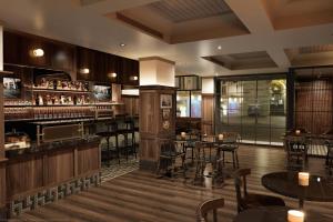 a restaurant with a bar with tables and chairs at The Queen’s Cue, Stratford, A Tribute Portfolio Hotel in Stratford