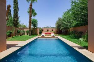 a pool in the backyard of a house with palm trees at Al Maaden Villa Hotel & Spa in Marrakesh