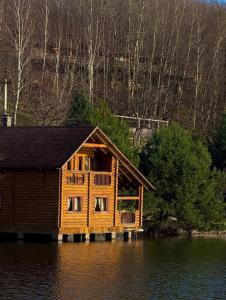 a log cabin on a lake in the water at Будиночок улюблений in Shirokoye