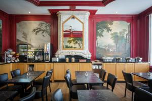 a restaurant with tables and chairs and paintings on the walls at Hotel Library Amsterdam in Amsterdam