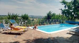 two people sitting in chairs next to a swimming pool at CA Assiolo in Senigallia