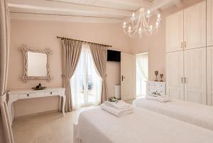 a white bedroom with two beds and a chandelier at Villa Frosso in Kalami +57 photos