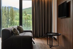 a living room with a couch and a large window at ETERNA HOTEL & SPA by Fomich in Palyanytsya