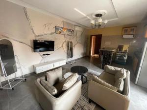 a living room with two couches and a tv at Résidences Quezia in Libreville