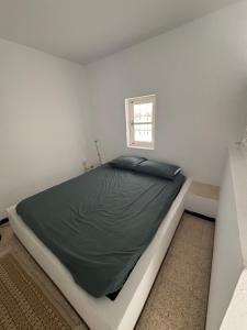 a bed in a white room with a window at Authentic, quiet and spacious house in El Guecheïne