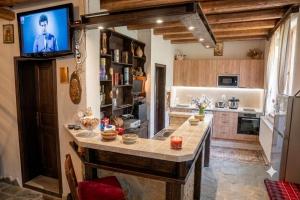 a kitchen with a large island with a tv on the wall at Костовският хан in Chepelare +23 photos