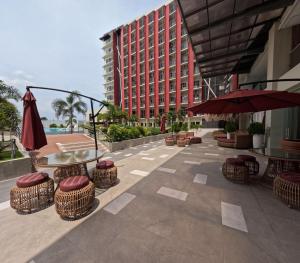 a patio with chairs and tables and a building at Mactan Airport 1BR Resort with Pool in Mactan Island