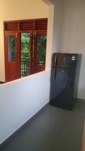 a kitchen with a refrigerator and a window with a door at 53 Villa in Habaraduwa Central