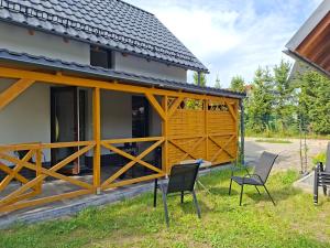 a house with a wooden gate and two chairs at Dom Trakt Słupski Sulęczyno in Sulęczyno