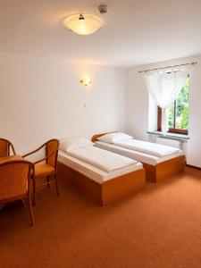 a bedroom with two beds and a chair and a window at Willa Agnieszki in Jagniątków
