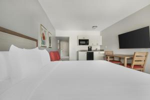 a bedroom with a large white bed and a kitchen at Hilton Vacation Club Palm Canyon Palm Springs in Palm Springs