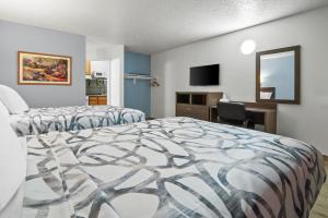 a bedroom with two beds and a desk and a mirror at Americas Best Value Inn Weatherford in Weatherford