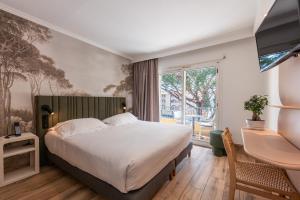 a bedroom with a bed and a desk and a window at Le Petit Prince in Sainte-Maxime