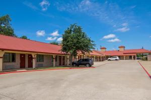 a row of buildings with cars parked in a parking lot at Americas Best Value Inn Weatherford in Weatherford