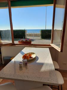 Ein Tisch mit einem Teller Orangen darauf vor einem Fenster in der Unterkunft Fronte Mare in Quercianella