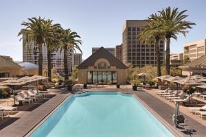 a pool with chairs and palm trees and a building at Signia by Hilton San Jose in San Jose