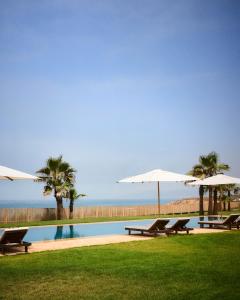 two picnic tables and umbrellas next to a pool at The Riad by Blue Waves in Agadir +64 photos
