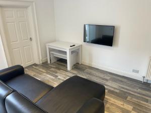a living room with a couch and a tv on a wall at Elder Park Apartments in Glasgow