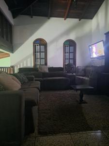 a living room with couches and a flat screen tv at Pousada Pontal de Santa Marina - Caraguatatuba in Caraguatatuba
