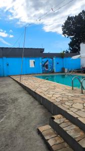 a blue building with a swimming pool with a blue wall at Pousada Pontal de Santa Marina - Caraguatatuba in Caraguatatuba