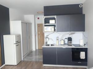 a kitchen with black cabinets and a white refrigerator at DN Fly & Stay in Wrocław