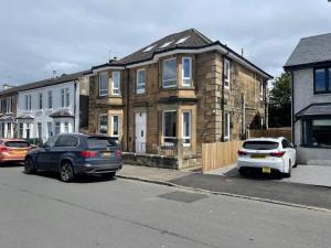 two cars are parked in front of a house at Elder Park Apartments in Glasgow