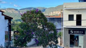 a tree in front of a building with purple flowers at Quarto Manjericão in Ibicoara