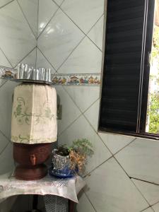 a lamp on a shelf with a plant and a window at Quarto Manjericão in Ibicoara