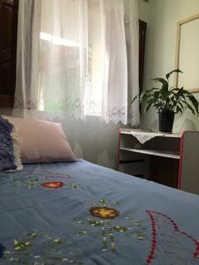 a bedroom with a bed with a blue blanket and a window at Quarto Manjericão in Ibicoara