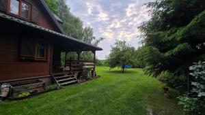 a house with a grass yard next to a building at Urokliwy domek Młynarze in Młynarze