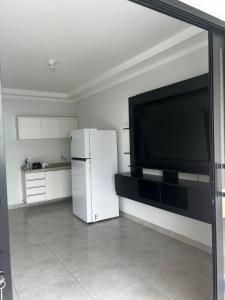a kitchen with a refrigerator and a large flat screen tv at Residential Florence Nightingale in Sorriso