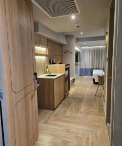 a kitchen with wooden cabinets and a room with a bed at The Quarter Ladprao by UHG in Bangkok