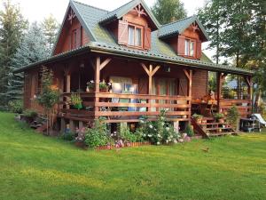 a large wooden cabin with a green yard at Urokliwy domek Młynarze in Młynarze +9 photos