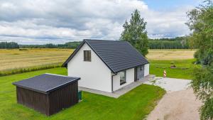a small white house with a black roof in a field at Sepa puhkemaja in Pärnu