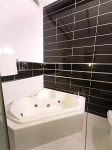 a white bath tub in a bathroom with black tiles at Hotel La Morada in Santo Domingo
