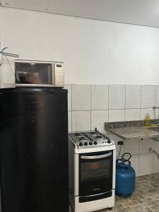 a microwave sitting on top of a stove in a kitchen at Quarto econômico e confortável in Hortolândia