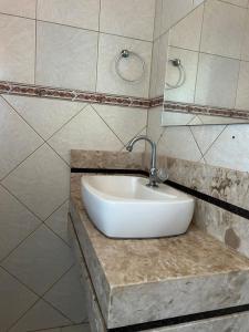 a bathroom with a white sink and a mirror at Quarto econômico e confortável in Hortolândia
