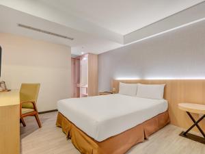 a bedroom with a large white bed and a desk at Guide Hotel Taipei Fuxing North in Taipei