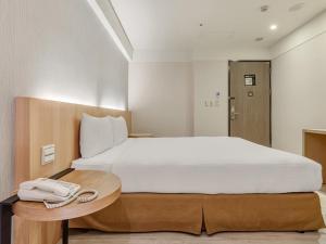 a bedroom with a bed with a phone on a table at Guide Hotel Taipei Fuxing North in Taipei