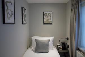 a hotel room with a bed with a pillow on it at Howard Winchester Hotel in London +25 photos