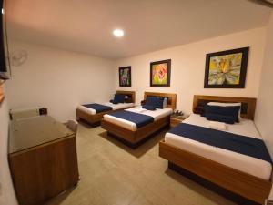 a hotel room with three beds and a television at Hotel Monarca in Medellín