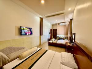 a hotel room with two beds and a flat screen tv at Khách Sạn Xuân Huỳnh 3 Sóc Trăng in Soc Trang