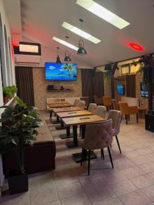 a restaurant with wooden tables and chairs and a flat screen tv at Balkan 024 in Subotica