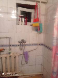 a white tiled bathroom with a shower at Izat in Karakol